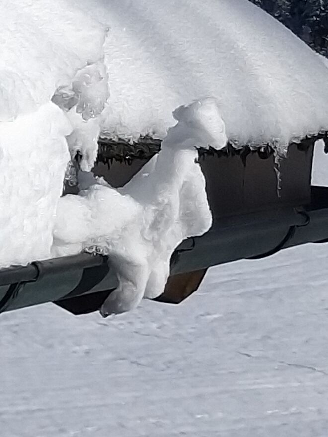 Kleiner Schneekobold sitzt auf der Dachrinne