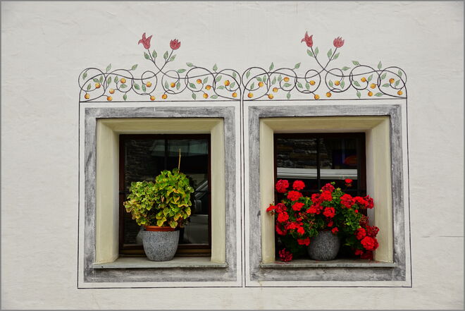 Schöne alte verzierte Fenster mit Blumenschmuck