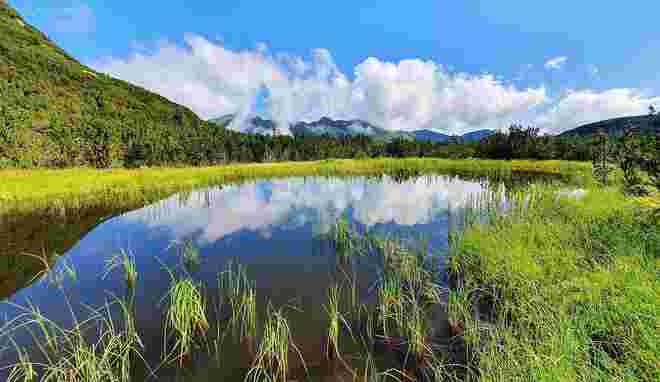 Wolken spiegeln sich im Bergsee