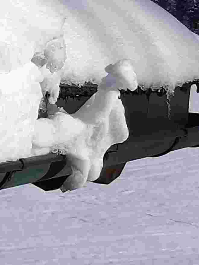 Kleiner Schneekobold sitzt auf der Dachrinne