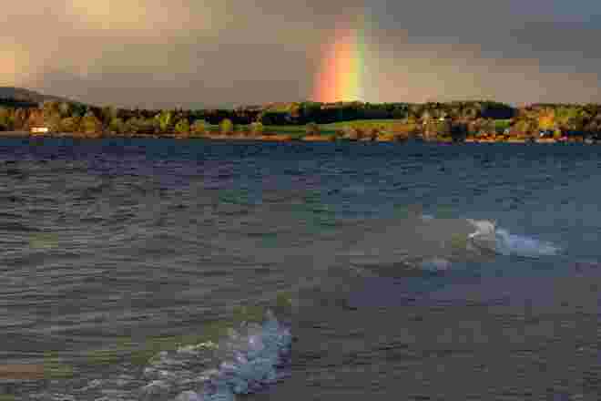 Regenbogen am See mit Wellen