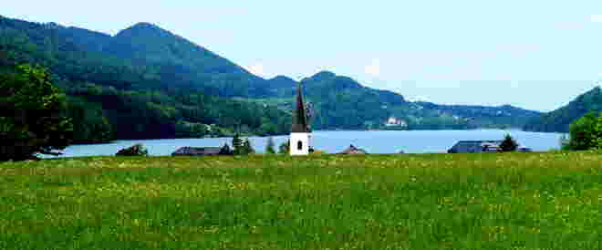 Blick über Wiese und See zum Schloss Fuschl