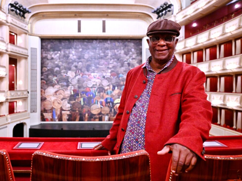 Holzobjekte blicken vom Vorhang auf die Staatsopern-Besucher