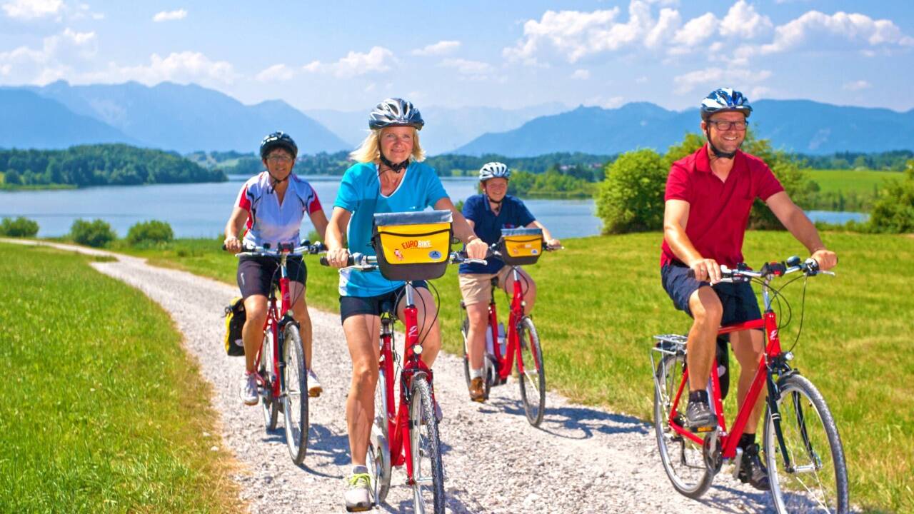 Feuerrote Tourenräder von KTM sind ein Markenzeichen des Radreiseveranstalters Eurofun Touristik aus Obertrum. Das Bild zeigt eine Gruppe am Riegsee in der Nähe von Murnau (Landkreis Garmisch-Partenkirchen) in Bayern auf dem Weg zum Gardasee.  