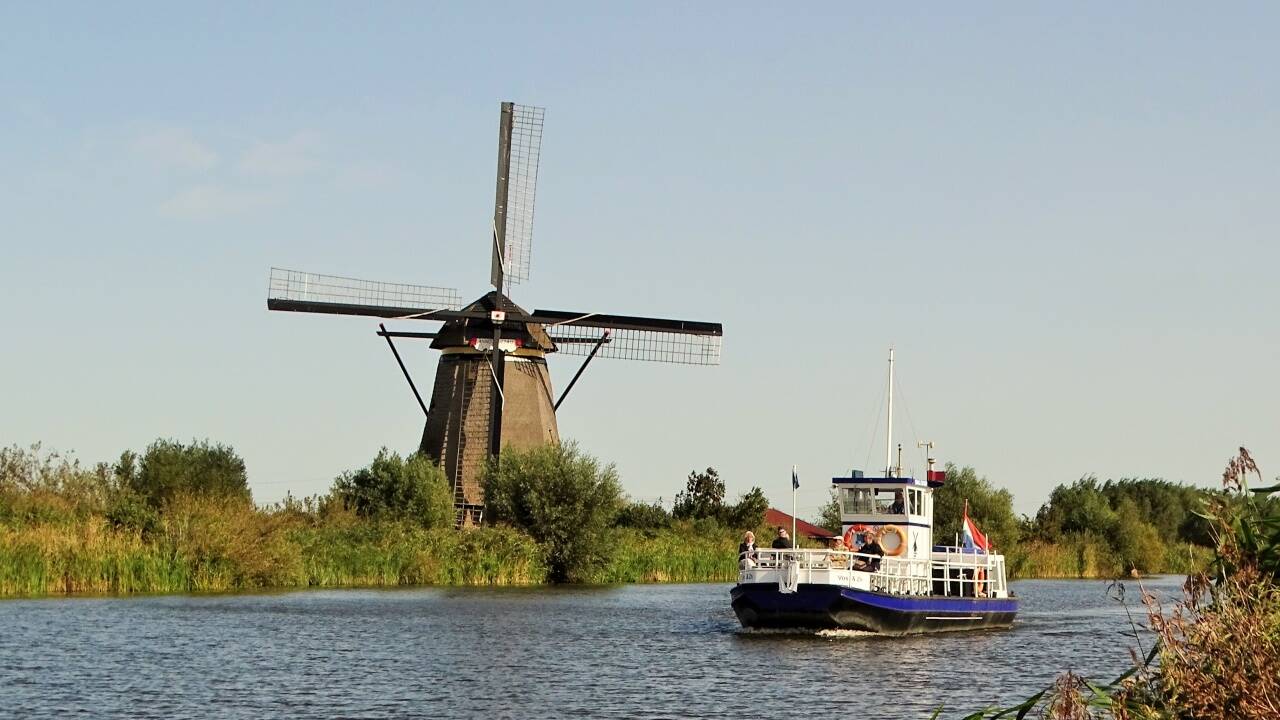 Neue Perspektiven vom Wasser aus: die historischen Windmühlen von Kinderdijk ragen imposant in den Sommerhimmel.  
