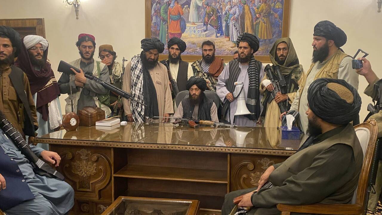 Talibankämpfer posieren am Schreibtisch des geflohenen afghanischen Präsidenten Aschraf Ghani im Präsidentenpalast in Kabul. Talibankämpfer posieren am Schreibtisch des geflohenen afghanischen Präsidenten Aschraf Ghani im Präsidentenpalast in Kabul.