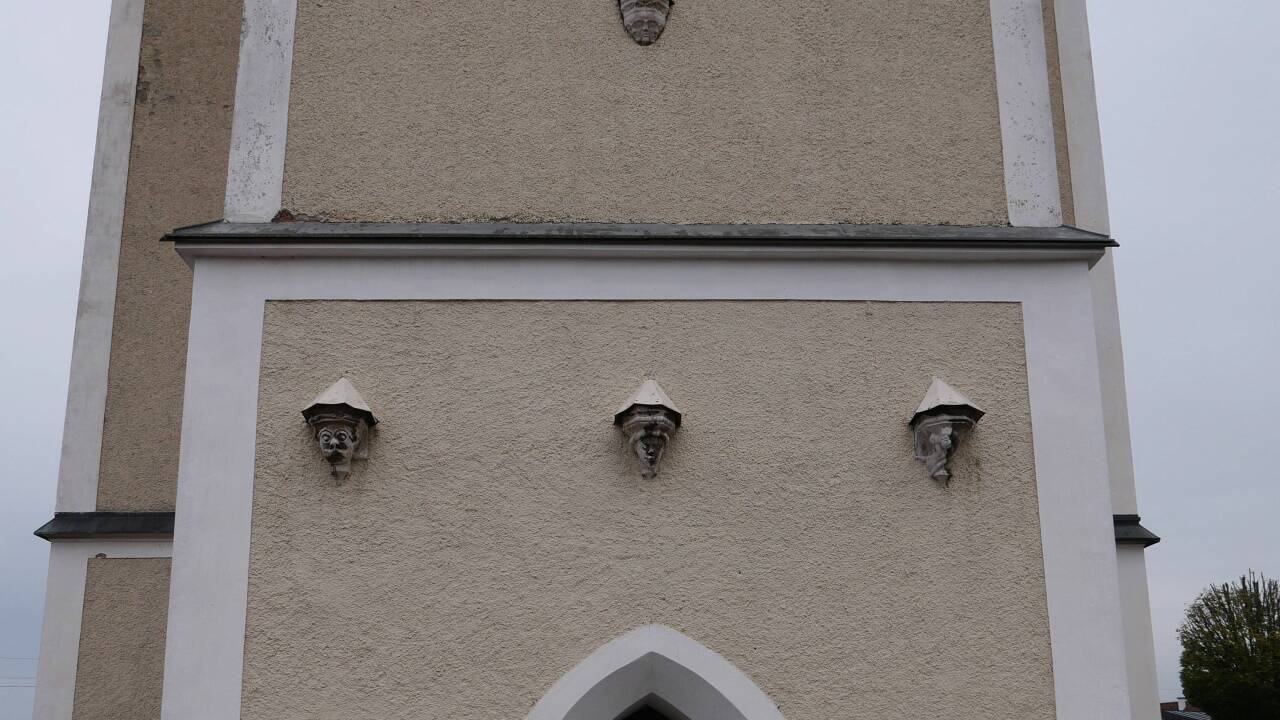 Die maskenhaften Gesichter über dem Kirchenportal.  