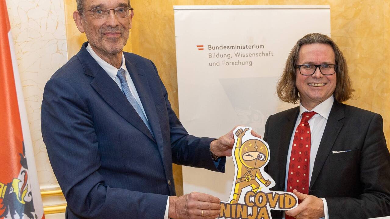 Der neue Minister Martin Polaschek bekam von Vorgänger Heinz Faßmann einen Covidninja aus Pappe. 