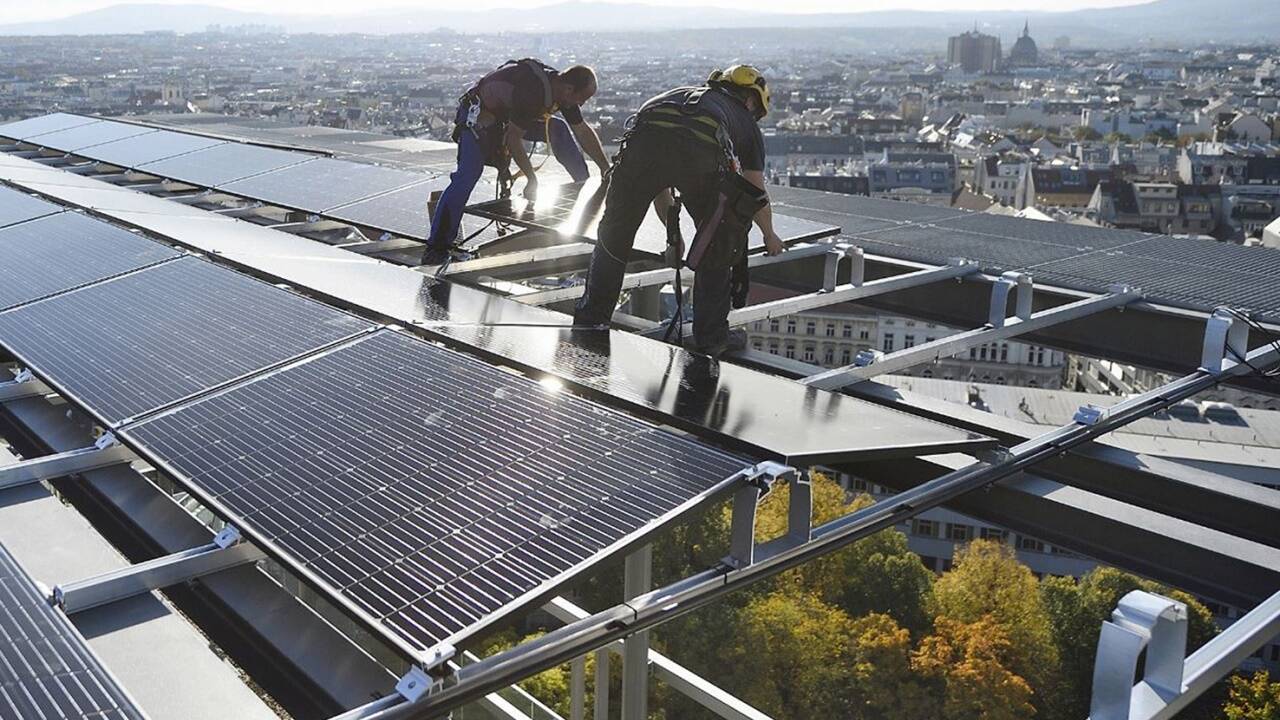  Monteure in schwindelerregender Höhe bei der Installation eine Photovoltaikanlage auf dem runderneuerten Haus des Meeres in Wien-Mariahilf. 