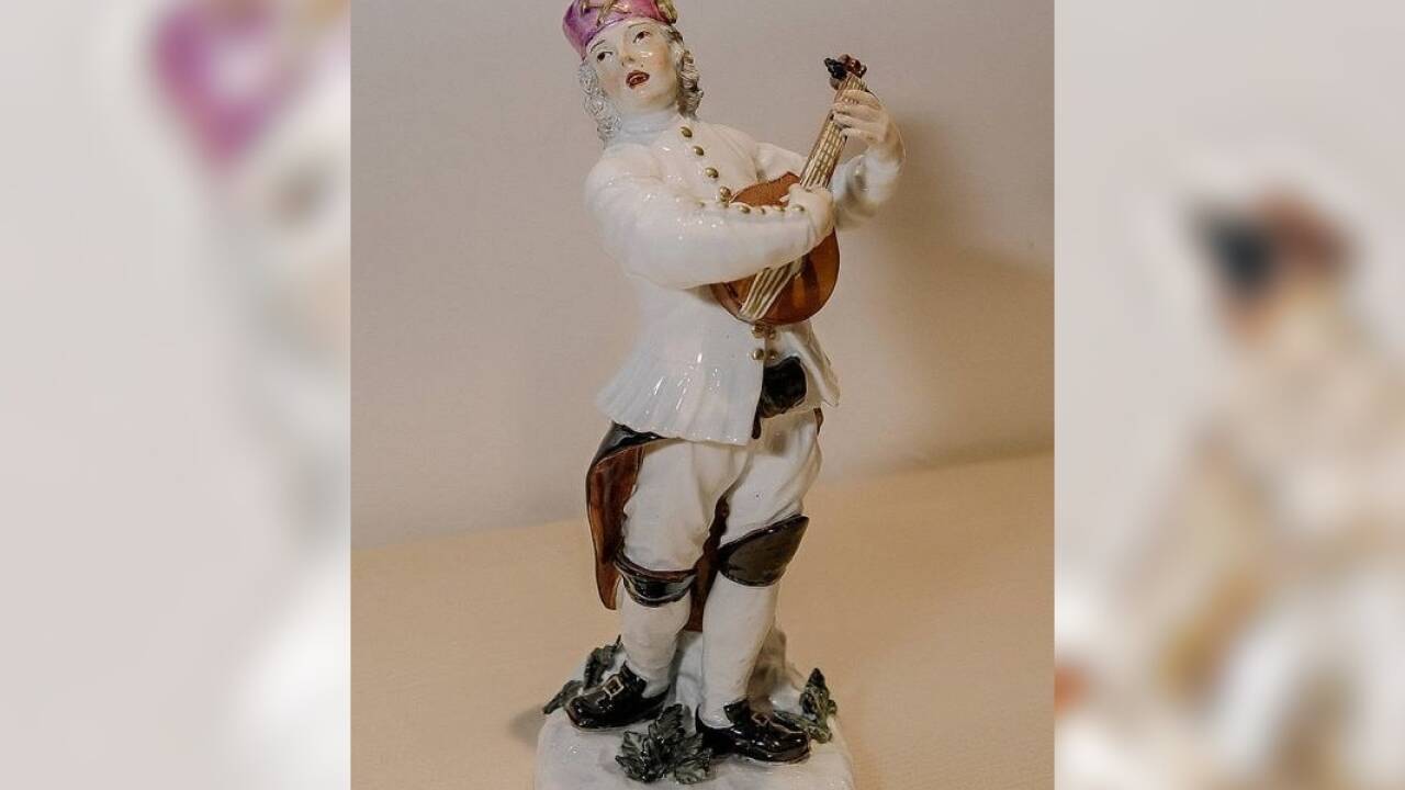 Der Bergmann aus Porzellan musiziert mit einem Cithrinchen.  