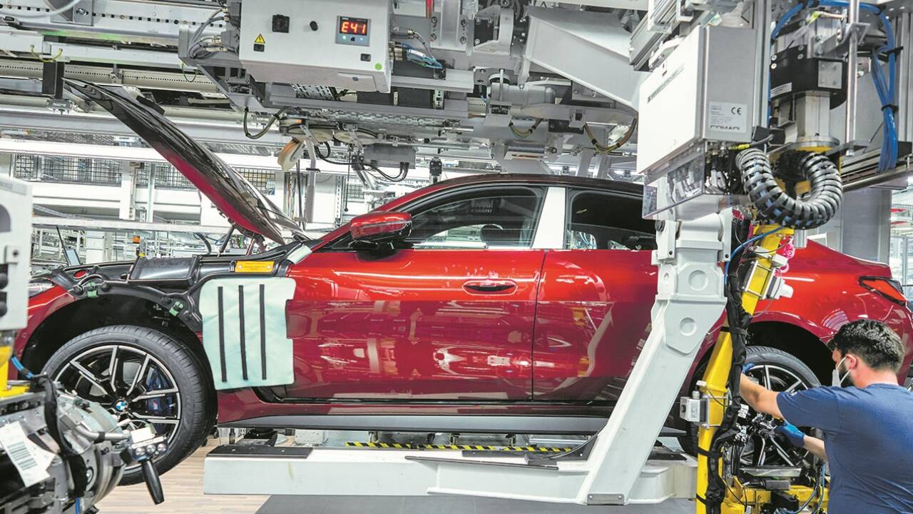 Roboter und Menschen arbeiten im BMW-Werk in München Hand in Hand.  