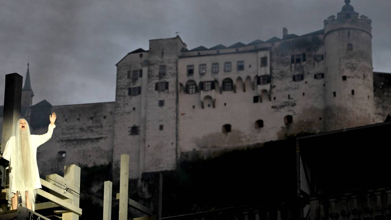 Mavie Hörbiger als Gott auf dem Domplatz, im Hintergrund die Festung Hohensalzburg.  