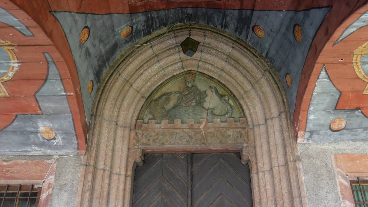 Das hölzerne Vordach ist auf der Innenseite mit Ornamenten bemalt.  