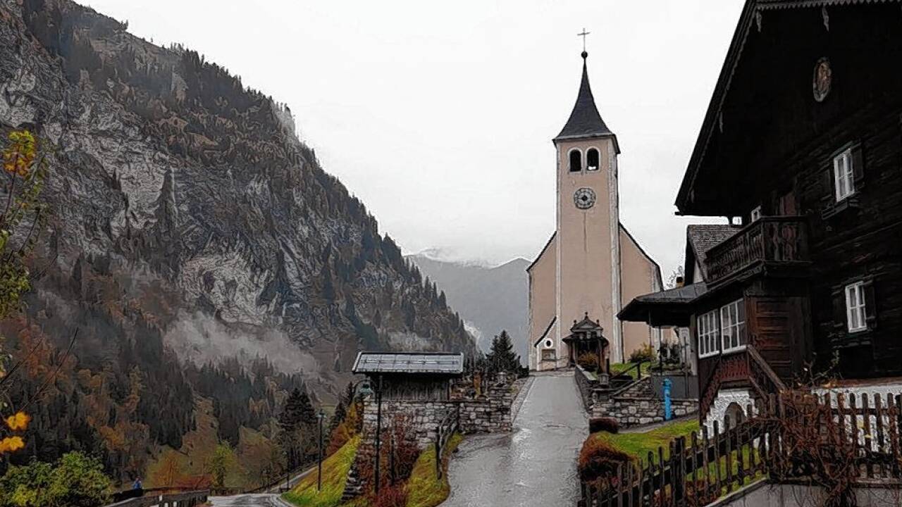 Die Pfarrkirche ist eine schlichte Erscheinung, die Hüttschlager Wand dominiert das Bild.  
