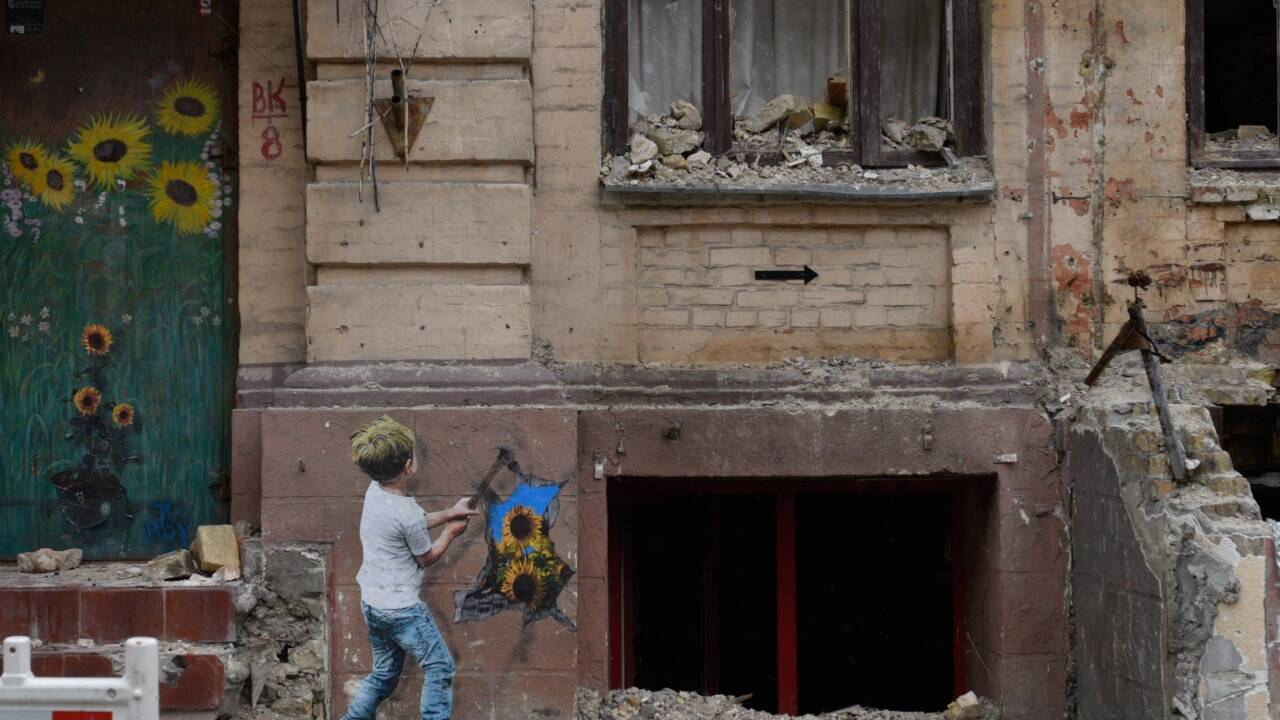 Eine Straße in Kyjiw: Der italienische Straßenkünstler TVBoy hat die zerstörte Fassade einer Hauswand verschönert. 
