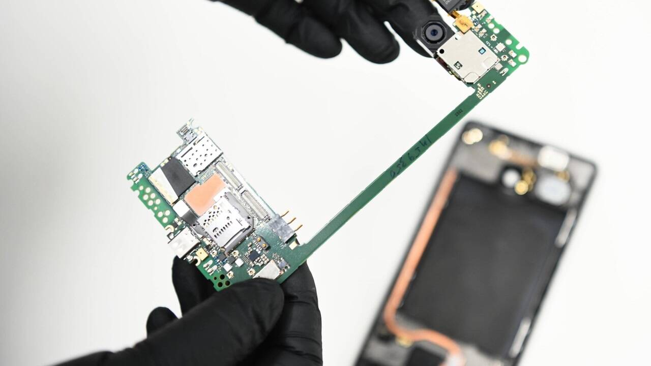 Auf der Suche nach elektronischer DNA: Ein IT-Forensiker mit der Hauptplatine eines Smartphones. Auf der Suche nach elektronischer DNA: Ein IT-Forensiker mit der Hauptplatine eines Smartphones.