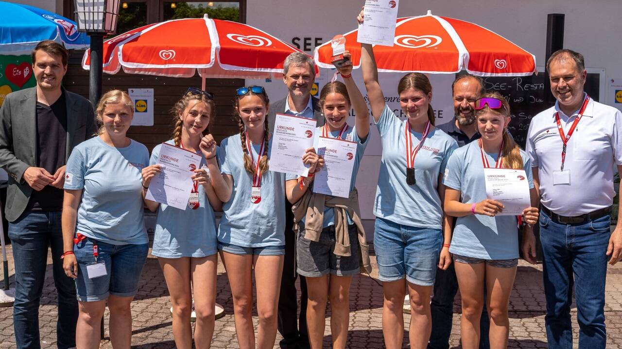 Siegerfoto mit den erfolgreichen „Atemberaubenden Pinzgauan“ (v. l.): LAbg. Luca Burgstaller, Jennifer Lochner (Trainerin und Begleitlehrerin der Schülerinnen), Stefanie, Lisa, Herbert Torta (Jugendrotkreuz-Landesleiter Kärnten), Magdalena, Marie, Wolfgang Schober (Operativer Jugendrotkreuz-Leiter Kärnten), Lara sowie Peter Kaiser (stv. Generalsekretär des Österreichischen Roten Kreuzes). 