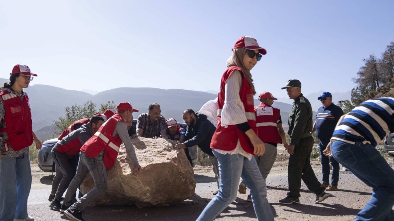 Mitarbeiter des Roten Halbmonds helfen dabei, einen Felsen von einer Straße zu räumen.  