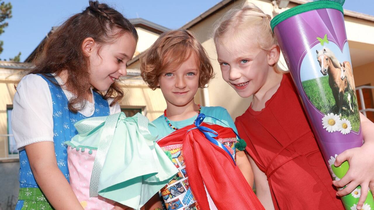 Taferlklassler Julia, Xaver und Franziska vor der Volksschule Leopoldskron-Moos. 