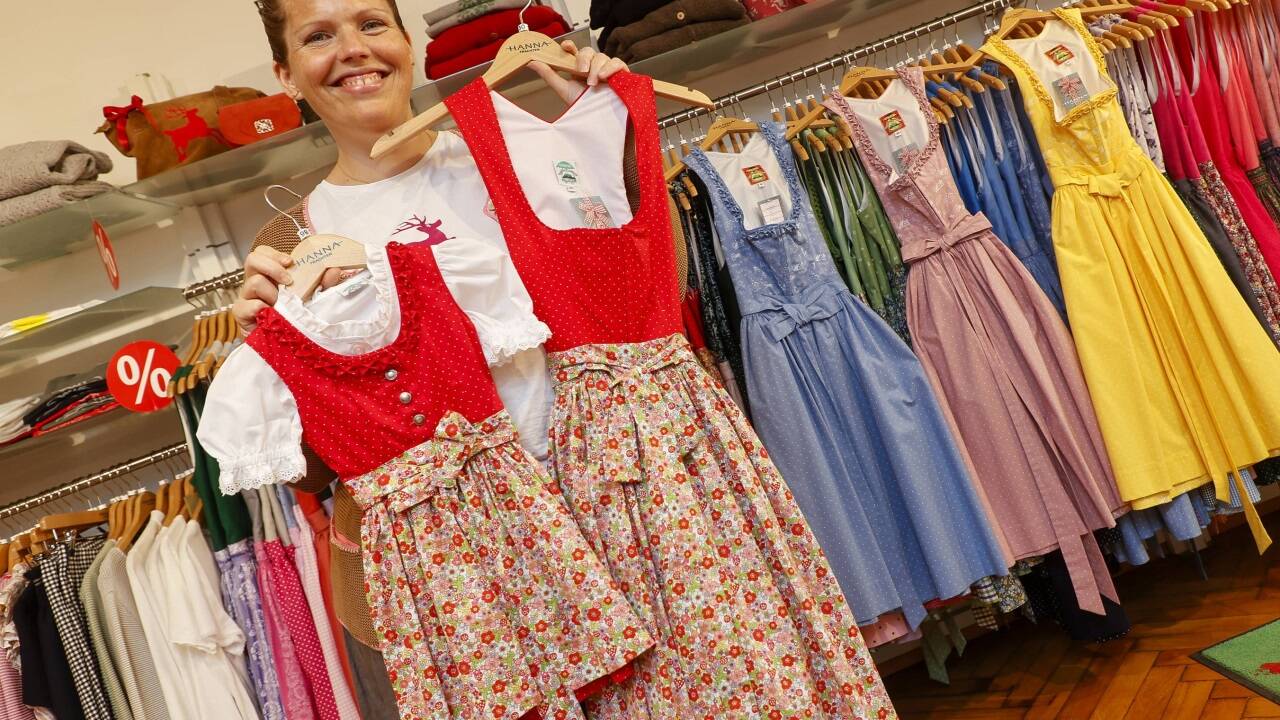 Constanze Kurz von Hanna Trachten in Salzburg mit einem der vier Kirtagsdirndl. Hinten die Dirndl aus dem Stoff mit dem neuen Bauernhofdruck.  