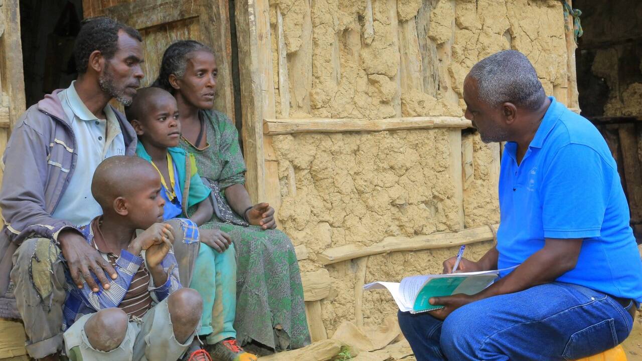 Projektleiter Berhanu Bedassa im Gespräch mit einem Landwirt und seiner Familie. Er hat bereits Saatgut erhalten.  