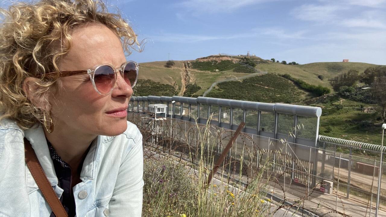 Das Bild zeigt Katja Riemann auf der spanischen Seite des Grenzzaunes der Stadt Ceuta an der nordafrikanischen Küste und der Straße von Gibraltar. 