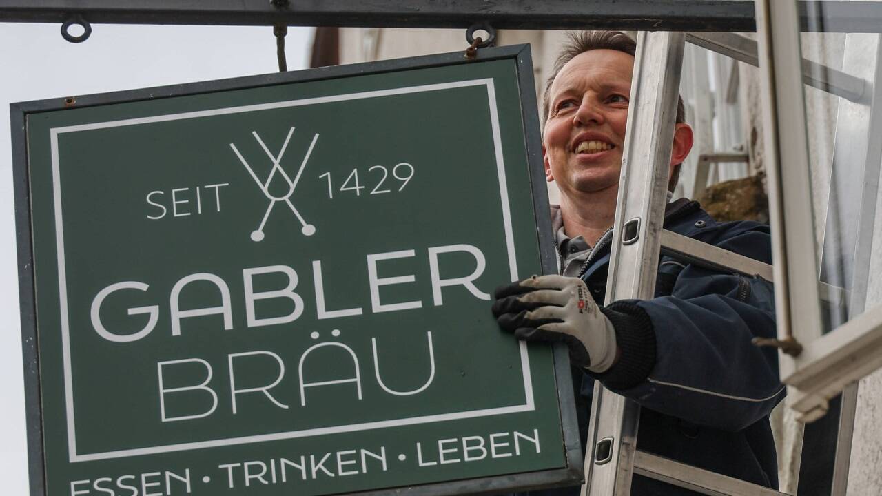 Christian Hauser von der Firma GP-Schilder montiert ein neues Gablerbräu-Schild an der Gebäudefassade. 