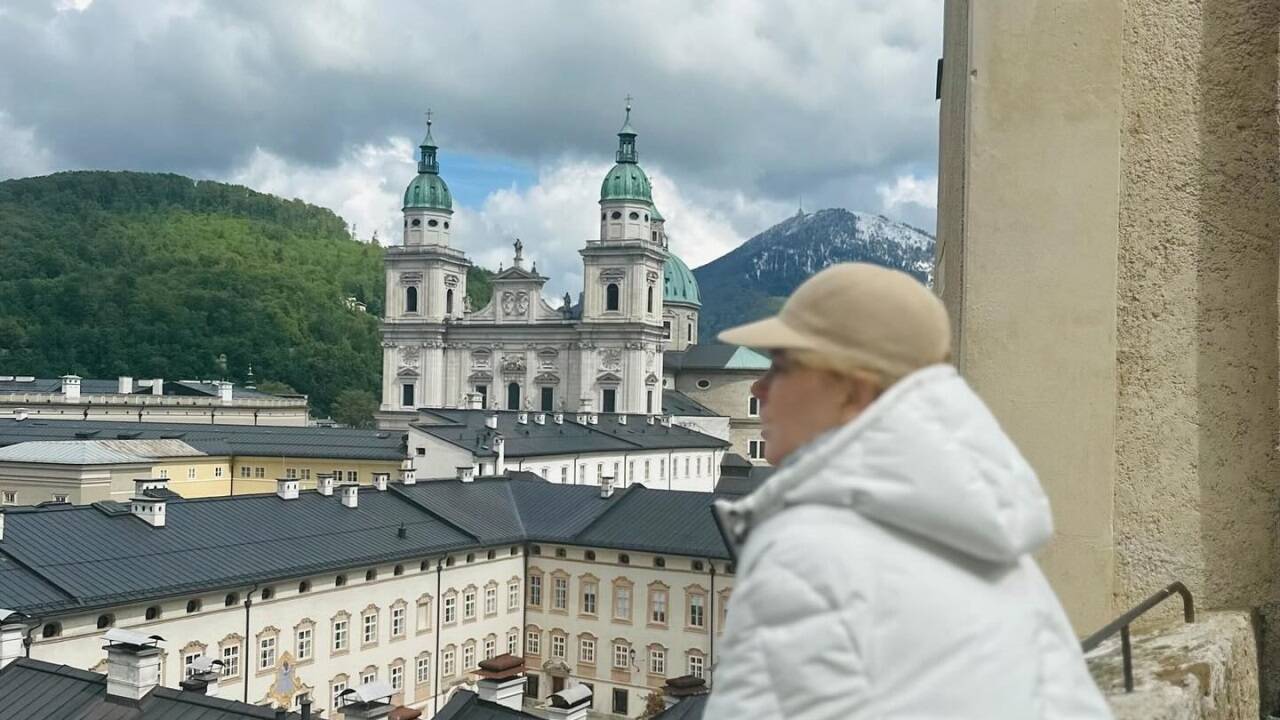 Nicole Kidman mit Ausblick auf die Stadt Salzburg und den Salzburger Dom. Im Hintergrund ein Bild der schneebedeckten Gaisbergspitze. 