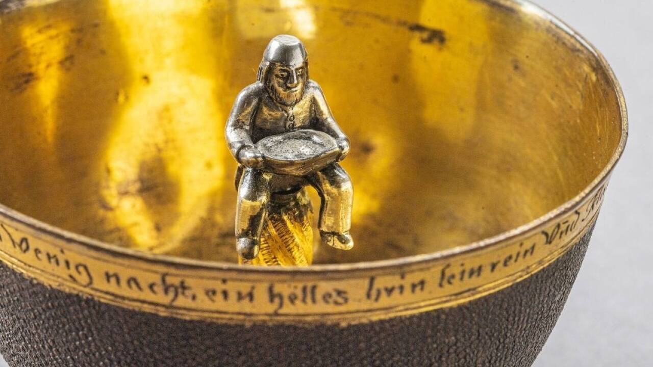 Ein Bergmann mit einem Fülltrog auf dem Schoß sitzt in der Mitte eines Tummlers aus Herrengrund, 18. Jahrhundert, Leihgabe der Achim-und Beate-Middelschulte-Stiftung. Am Lippenrand steht: „Im hardten Eisen mich hat gemacht zu weichen Kupfer in Wenig nacht, ein helles brinlein rein Und klar in Herren Grundt ist gewißlich Wahr!“ 
