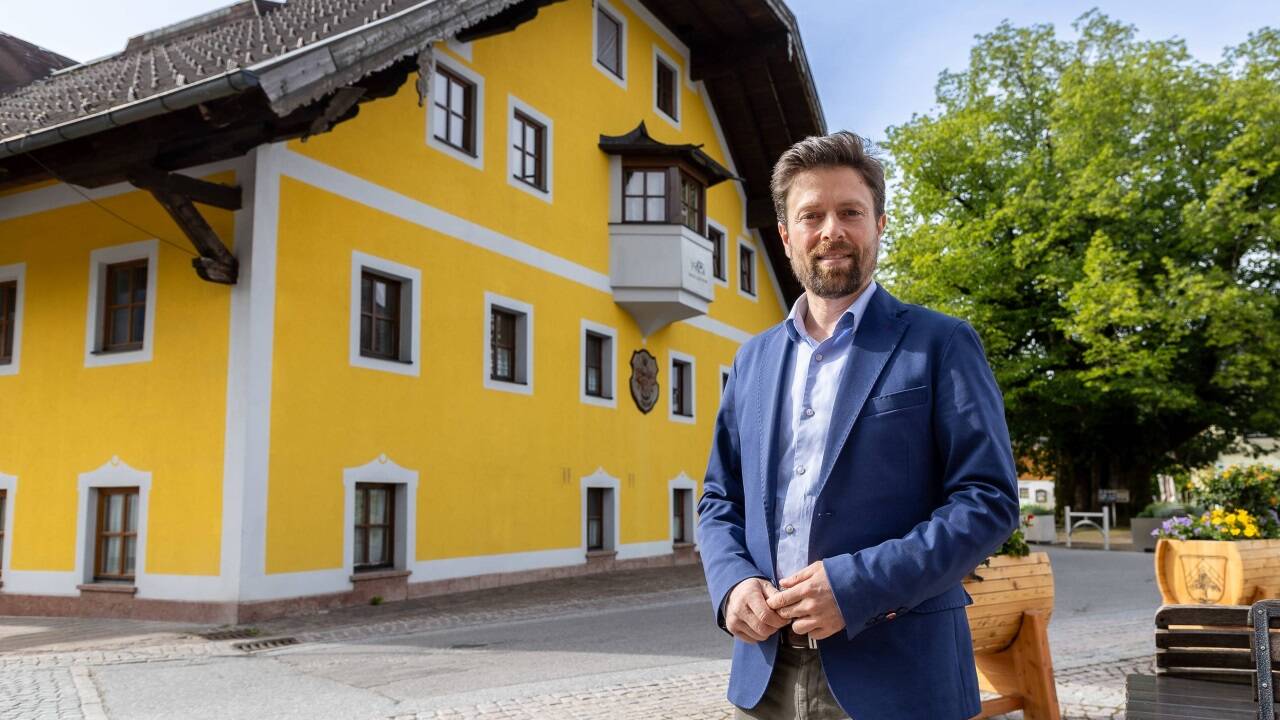 Ortschef Gerald Klaushofer vor dem ehemaligen Hotel, das nun Arbeitnehmer beherbergt, und der Dorflinde. 