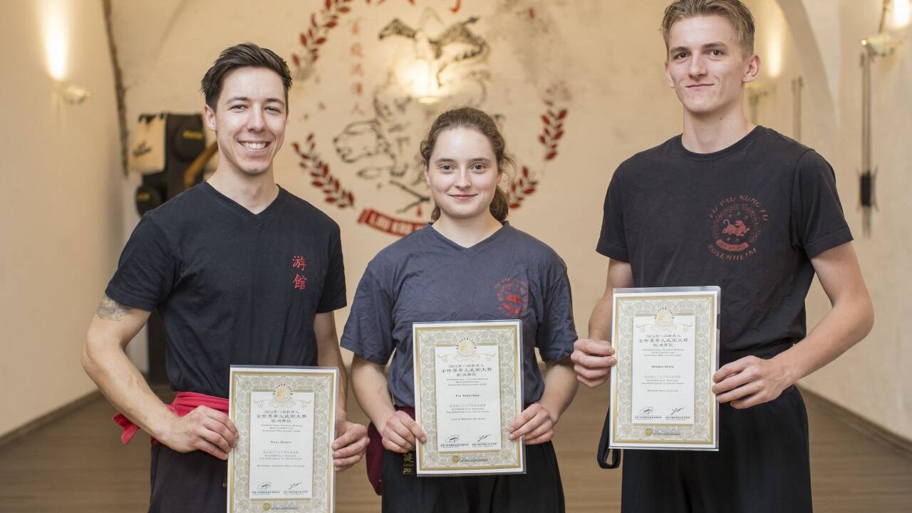 Paul Huber, Schülerin Pia Trautner und Kung-Fu-Lehrer Dennis Spies (v. l.) mit ihren Zertifikaten, die sie nach dem Erfolg in Dresden überreicht bekamen.  
