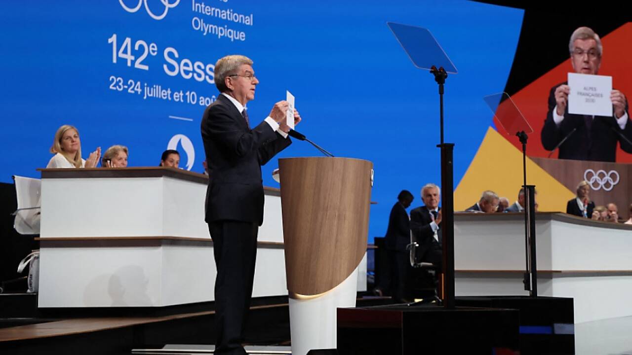 IOC-Präsident Bach hält den Entschluss hoch 