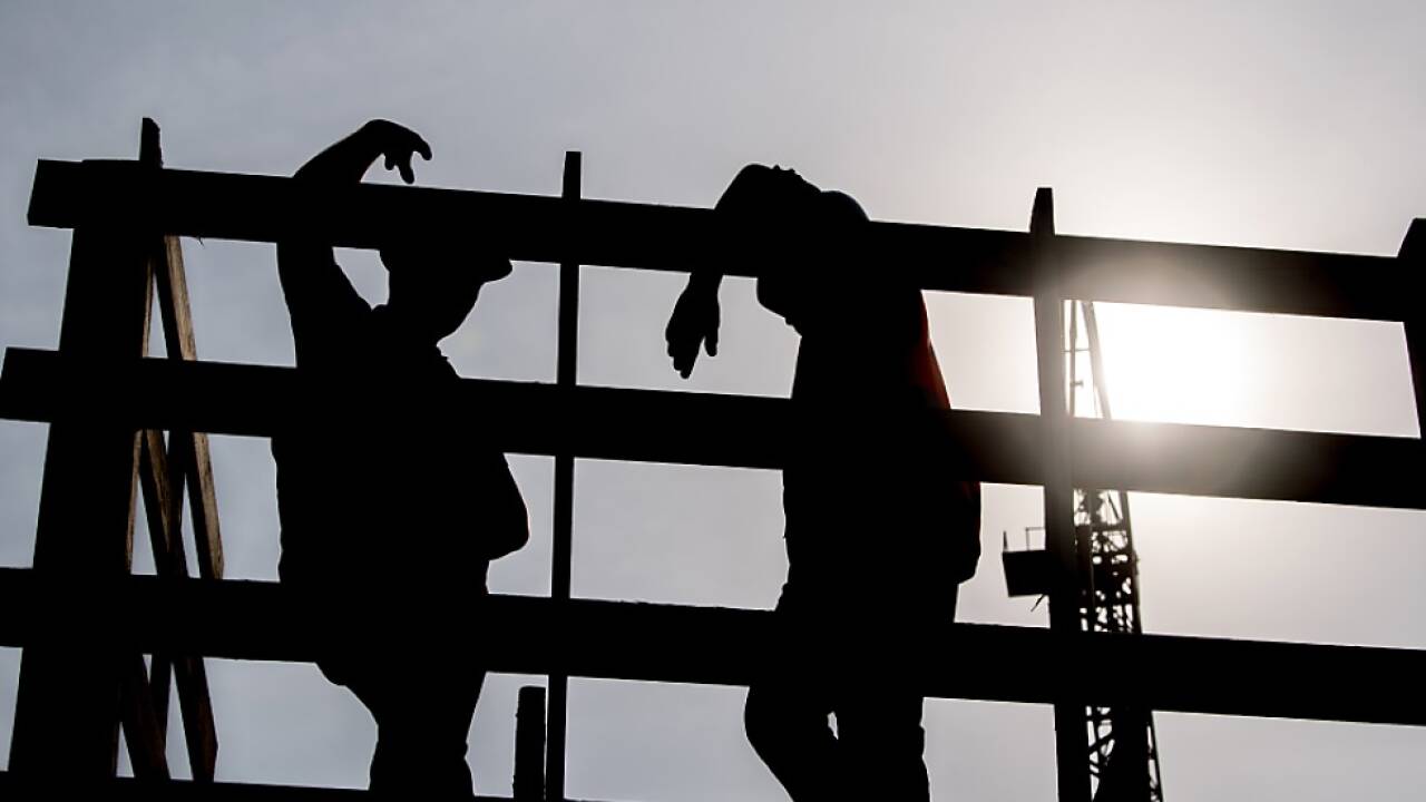 Zwei Arbeiter auf einem Gerüst auf einer Baustelle 
