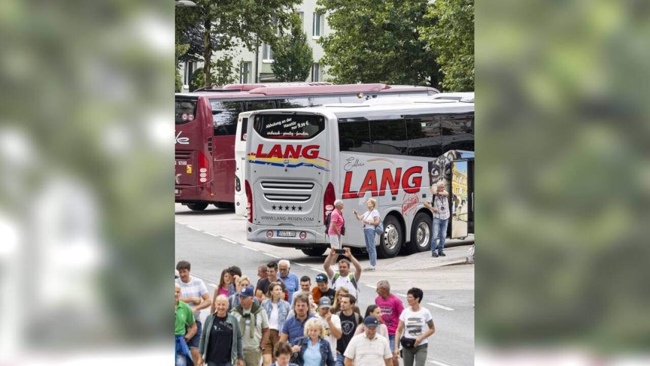 Bustouristen versammeln sich am Busparkplatz.  