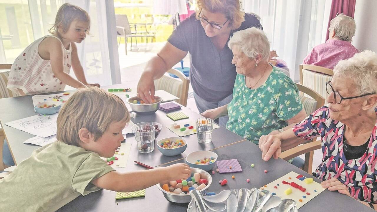 Kleinkinder und Bewohner des Kreisaltenheims Palling basteln gemeinsam unter der Anleitung von Kursleiterin Bernadette Leitner-Mauracher (stehend). 