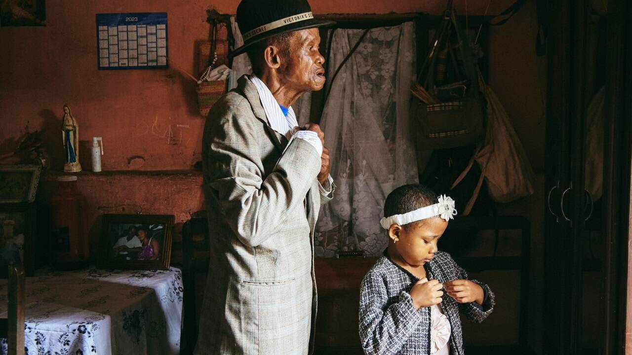 Großvater Paul Rakotazandriny (91), der an Demenz leidet, und seine Enkelin Odliatemix Rafaraniriana (5) bereiten sich am Sonntagmorgen in seinem Haus in Antananarivo, Madagaskar, für den Gottesdienst vor. 12. März 2023  Großvater Paul Rakotazandriny (91), der an Demenz leidet, und seine Enkelin Odliatemix Rafaraniriana (5) bereiten sich am Sonntagmorgen in seinem Haus in Antananarivo, Madagaskar, für den Gottesdienst vor. 12. März 2023