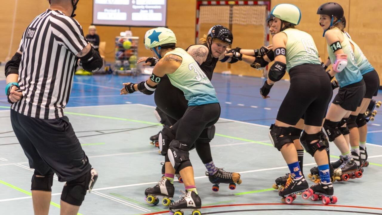 Beim Roller Derby ist Körpereinsatz gefragt. So wie hier beim Match der Salzburgerinnen (schwarze Jerseys) gegen die Steel City Rollers aus Linz. Ein Schiedsrichter überwacht das Geschehen. 