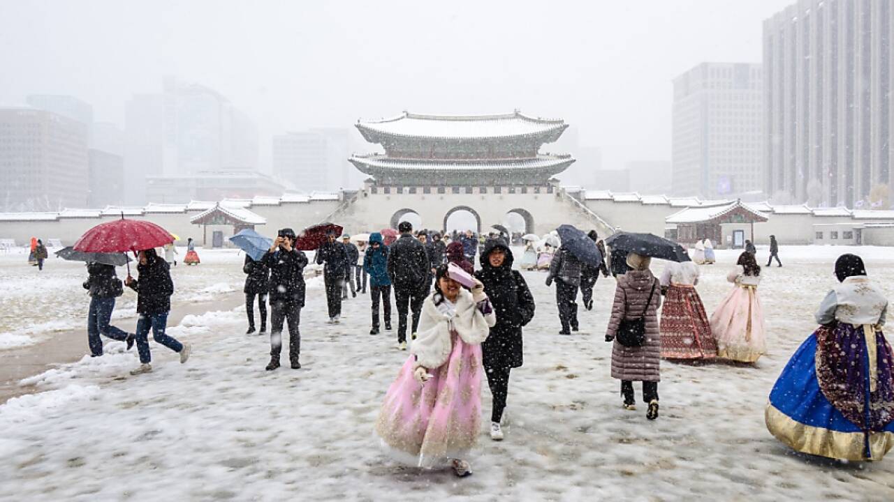 Traditionell gekleidete Besucher beim Gyeongbokgung Palast im Schnee 