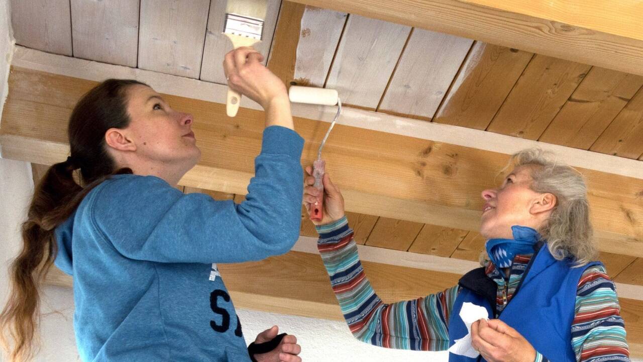 Die Holzdecke erhält einen neuen Farbanstrich, wirkt dadurch heller und passt zum weißen Mobiliar. 