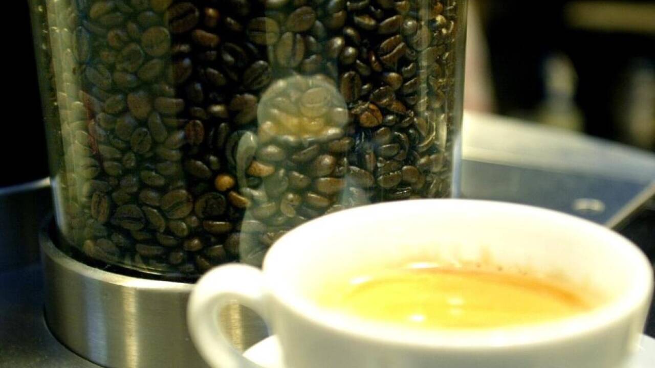 Frisch gebrühte Tasse Kaffee vor einem Behälter mit Kaffeebohnen  Frisch gebrühte Tasse Kaffee vor einem Behälter mit Kaffeebohnen