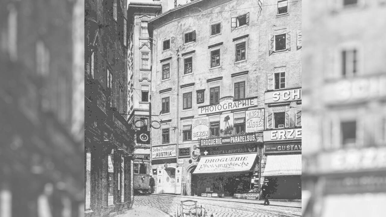 Das Haus Platzl 3 mit der „Droguerie Theophrast Paracelsus“, um 1910. Ganz links ist die 1909 neu eingeführte „Gelbe Elektrische“ auf dem Weg zur Haltestelle Platzl zu erkennen. 
