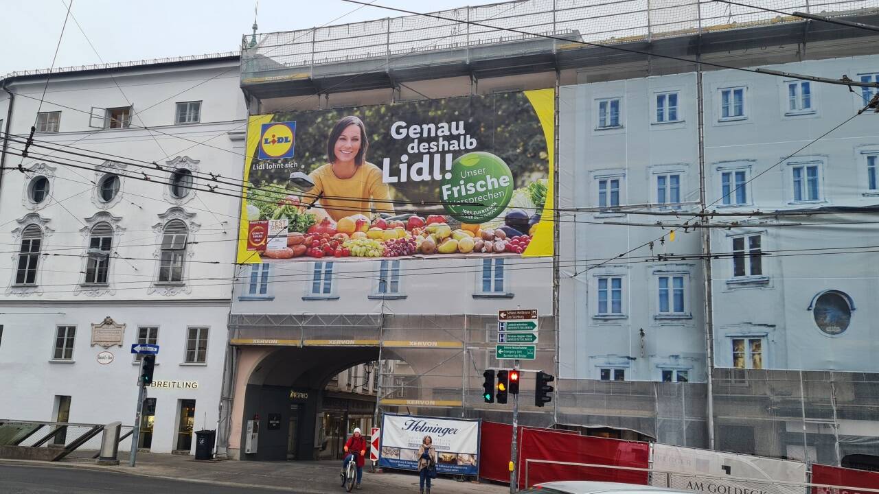 An einem der prominentesten Orte in der Stadt Salzburg prangt ein riesiges Werbeplakat auf der Fassade. 