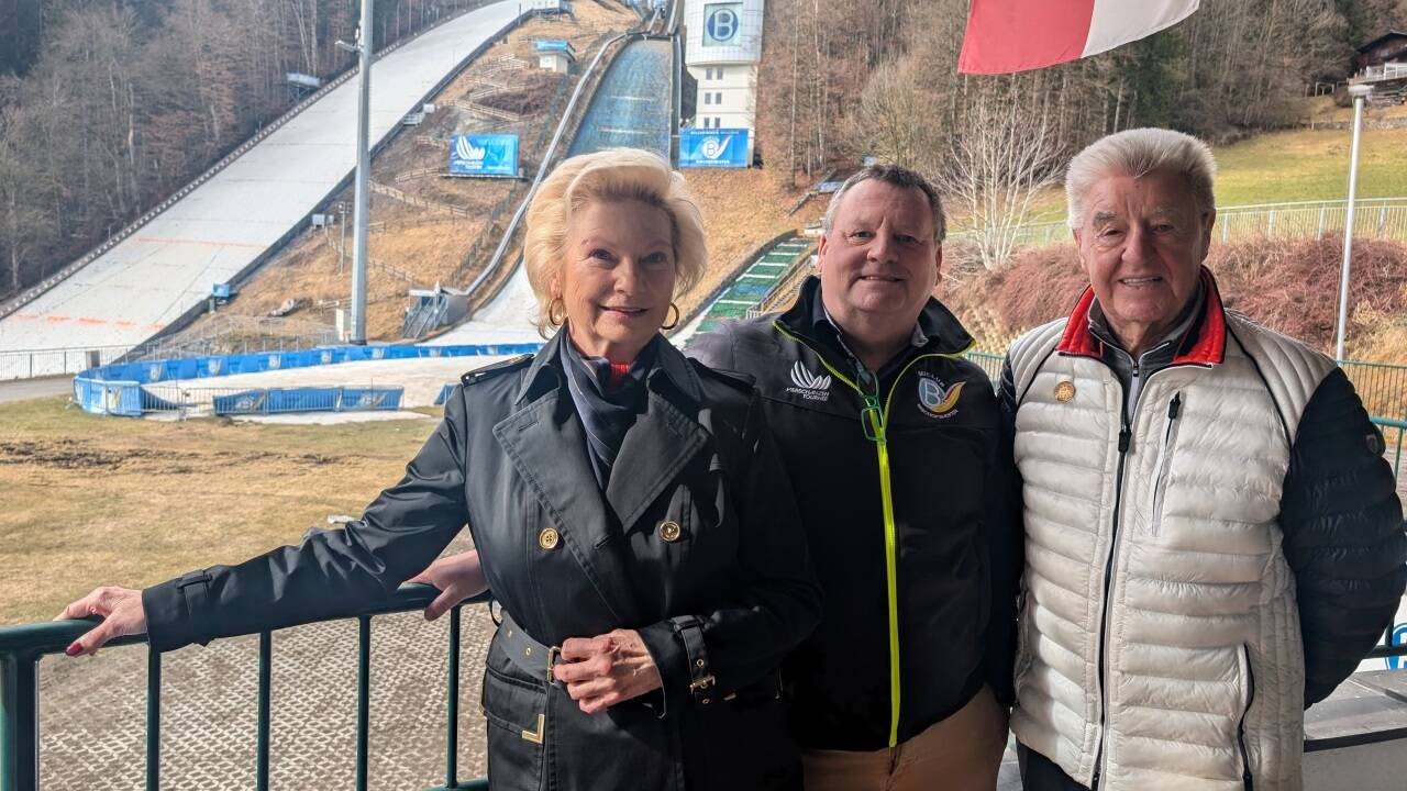 Die Tochter von Skispringer Josef Bradl, Karin Pritzi mit Ehemann Josef (rechts) und Präsident des Skiclub Bischofshofen, Manfred Schützenhofer. Im Hintergrund: Paul-Außerleitner-Schanze im „Sepp Bradl Stadion“ in Bischofshofen. 