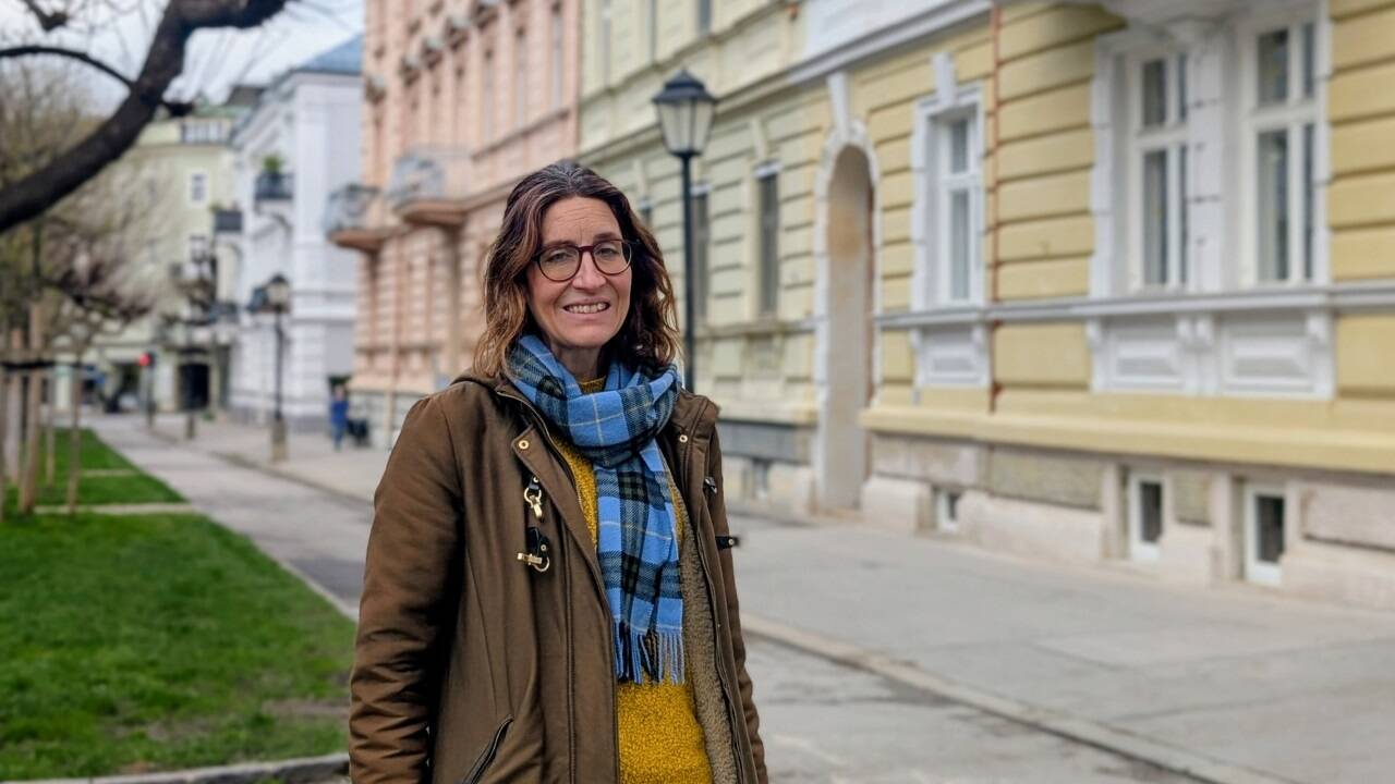 Bauhistorikerin Dagmar Redl-Bunia in der Franz-Josef-Straße in Salzburg, wo eine Fassade mit Förderung saniert werden konnte. Auf der gegenüberliegenden Straßenseite bröckelt eine Fassade eines geschützten Gebäudes ab. 