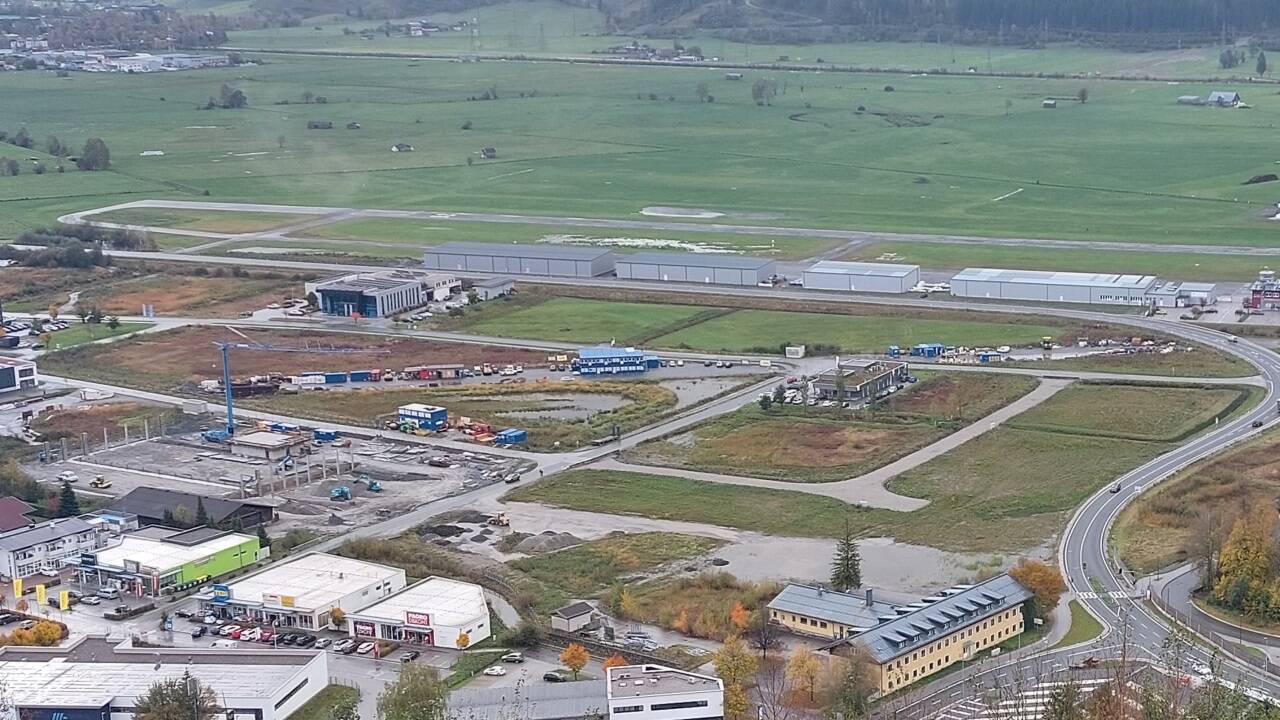 Das Gewerbegebiet mit dem neuen Flugplatz im Hintergrund im Herbst 2024. Das gelbe Gebäude rechts unten ist die ehemalige Fliegerschule. 