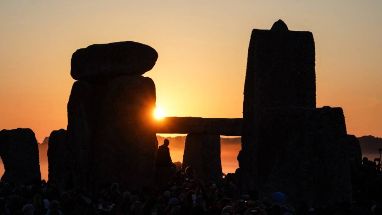 Menschen in Roben und Blumenkränzen im Haar 