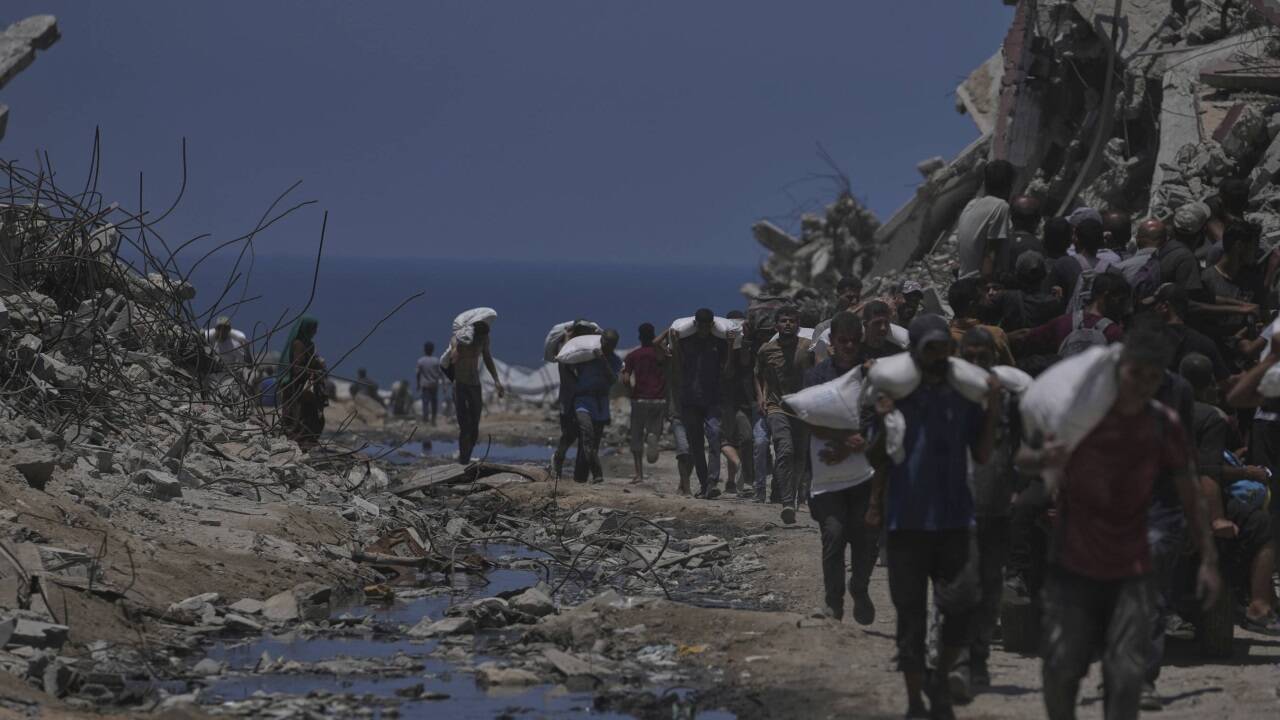 Menschen im Gazastreifen mit Mehlsäcken, die sie von einem Hilfskonvoi bekommen haben. Menschen im Gazastreifen mit Mehlsäcken, die sie von einem Hilfskonvoi bekommen haben.