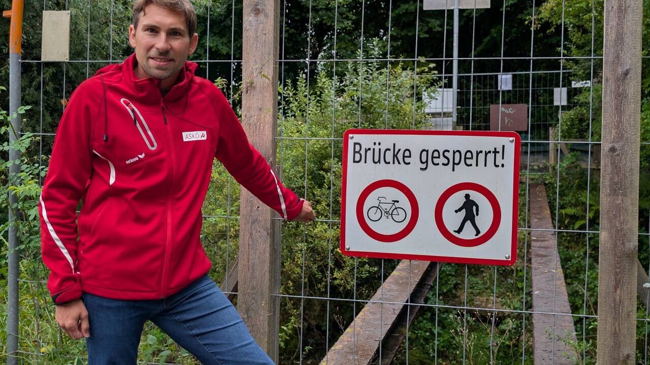 Gemeinderat Sebastian Lankes (SPÖ) vor der einstigen Gehwegbrücke am Bachwinkelweg über den Alterbach. Der Steg ist seit Juni 2023 gesperrt. Die Konstruktion ist längst abgetragen. Ende September beginnt der Bau der neuen Brücke.  