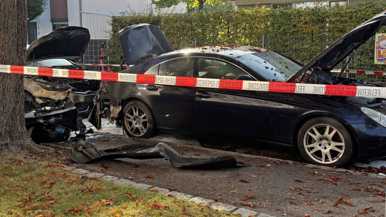 Zwei PKW, die gebrant hatten, stehen in einer Straße. Ein Brand in einem Münchner Einfamilienhaus hat einen Großeinsatz von Polizei und Feuerwehr ausgelöst. 