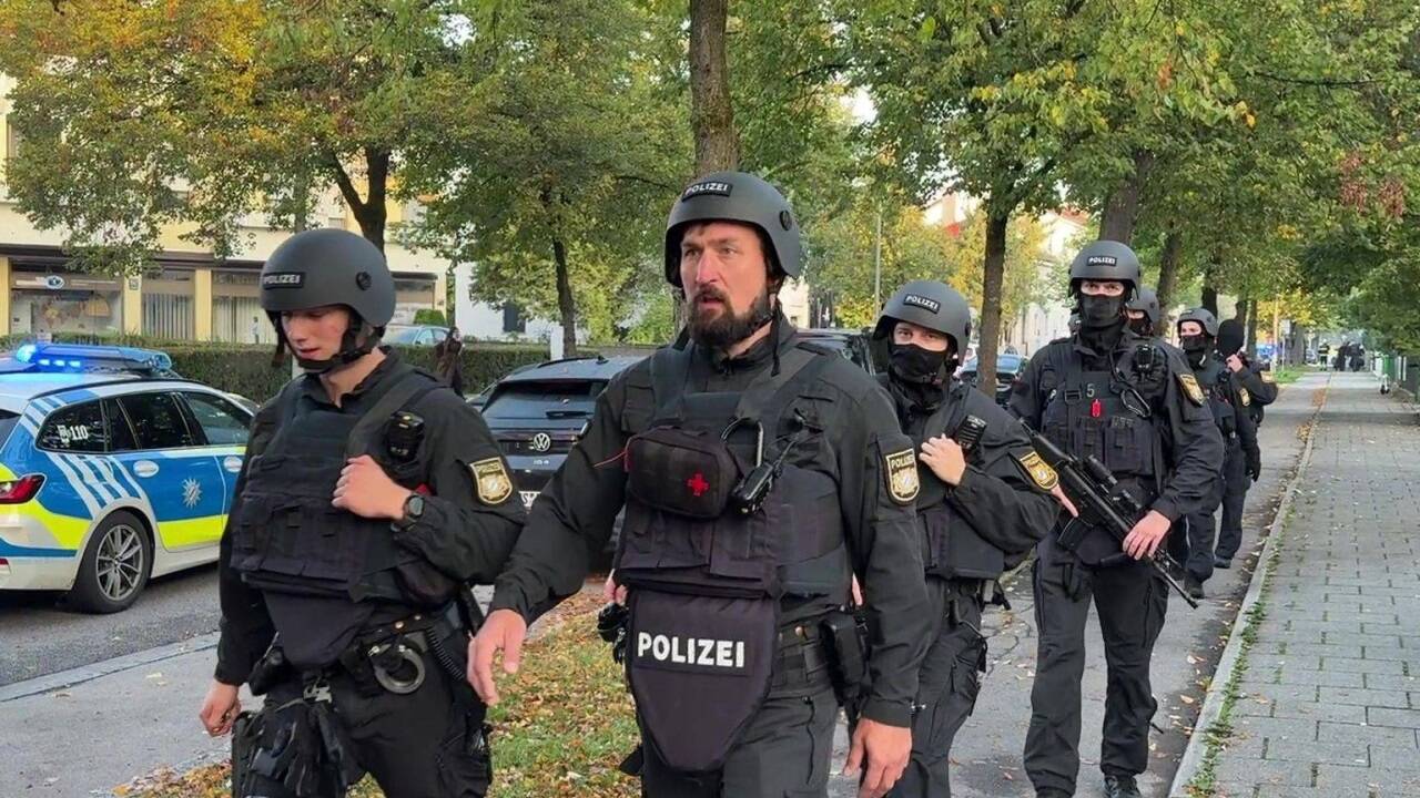 Polizisten mit Schutzwesten gehen über einen Fußweg. 